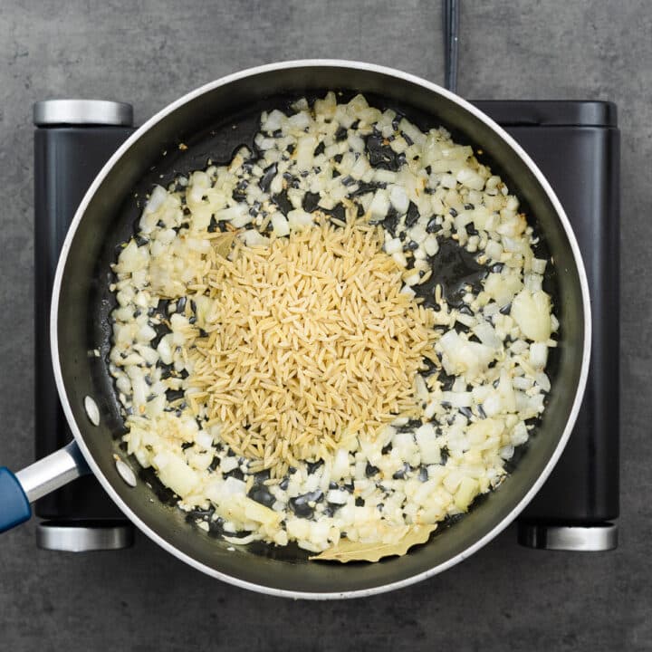 A pan with aromatics and orzo.