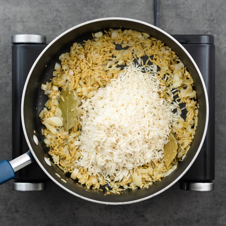 A pan with aromatics, orzo, and rice.