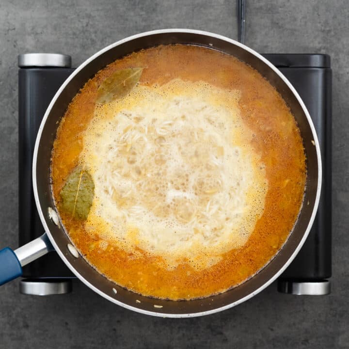 A pan with rice and orzo mixture cooking in chicken broth.
