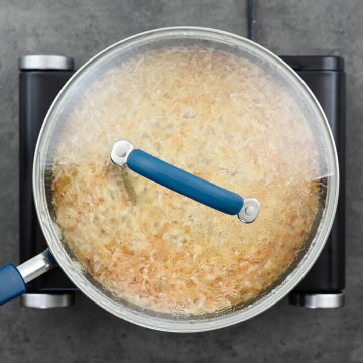 A pan with rice and orzo mixture cooking with the lid closed.