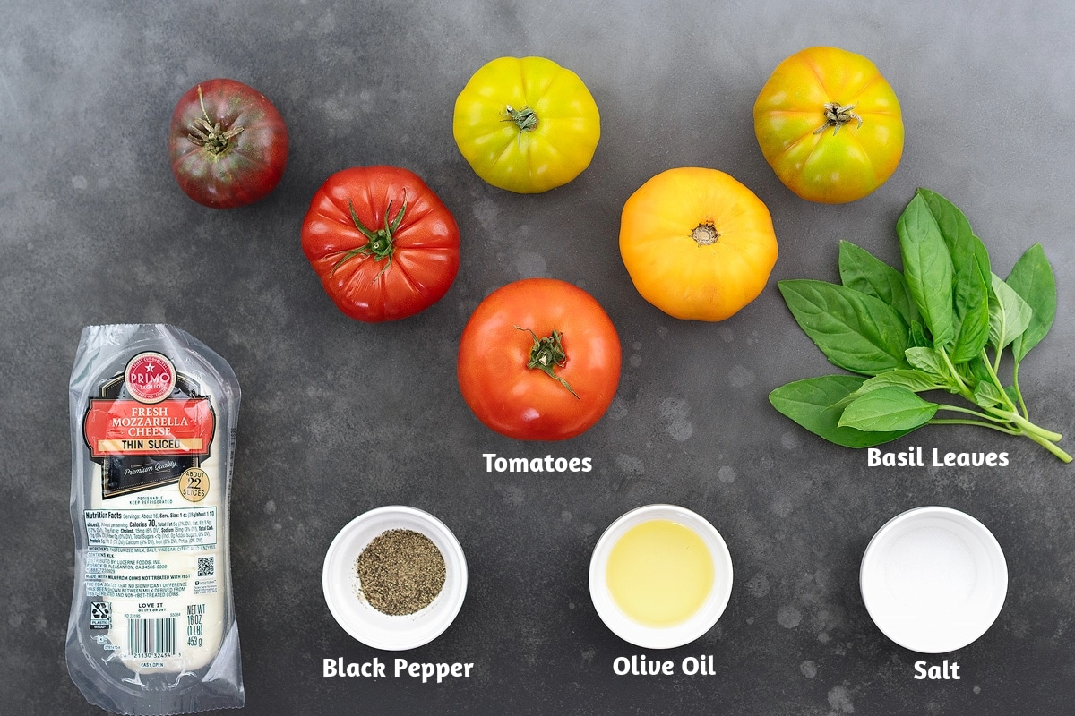 Ingredients for Caprese salad: fresh tomatoes, basil leaves, fresh mozzarella cheese, black pepper, olive oil, and salt.