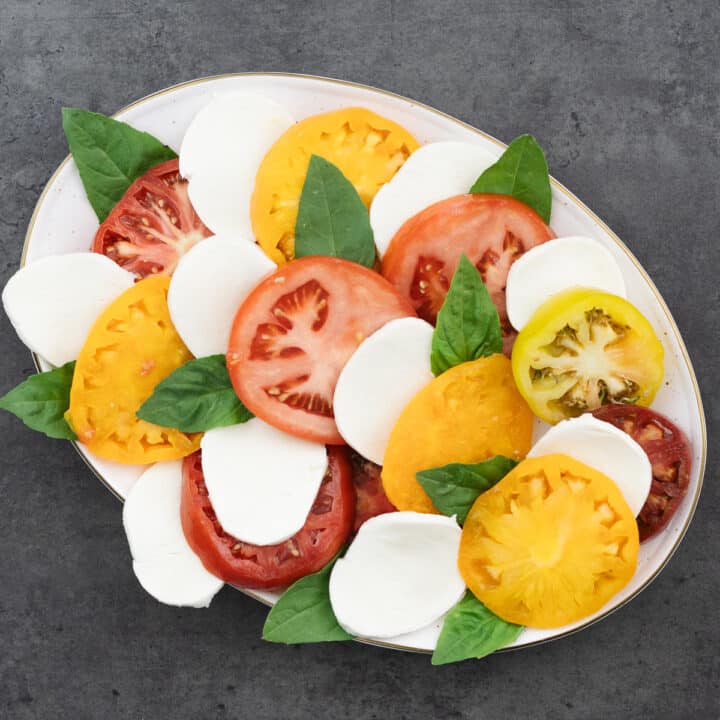 A serving plate showcasing an arrangement of sliced tomatoes, fresh mozzarella, and basil leaves.