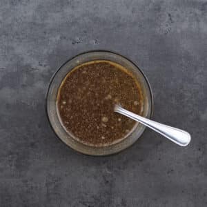 A bowl with stir-fry sauce and a spoon.