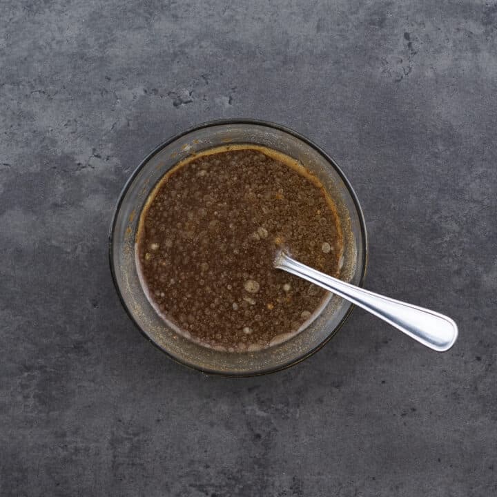 A bowl with stir-fry sauce and a spoon.