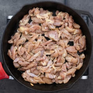 A cast iron pan with marinated chicken pieces.