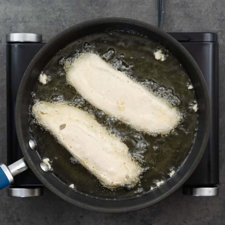 A pan with battered fish frying in oil.