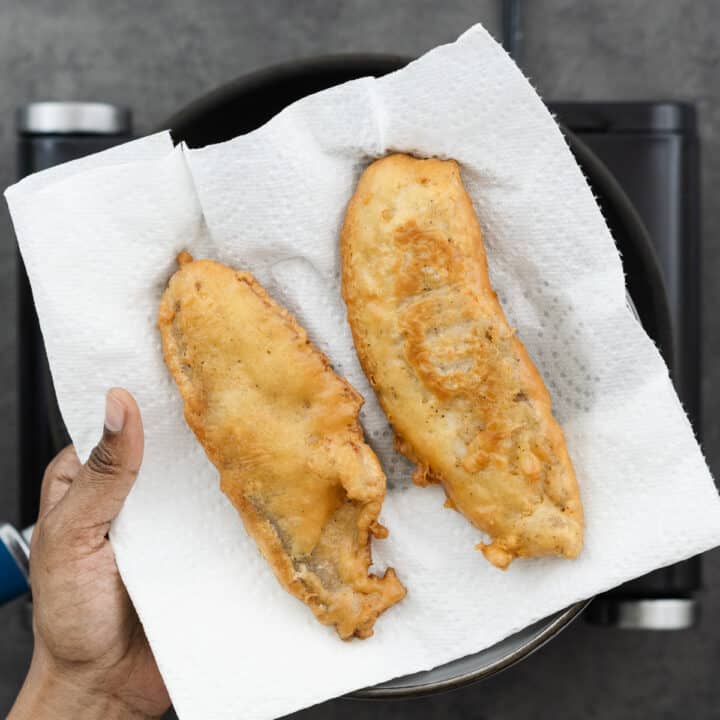 Golden brown fried fish on a paper towel-lined tray.