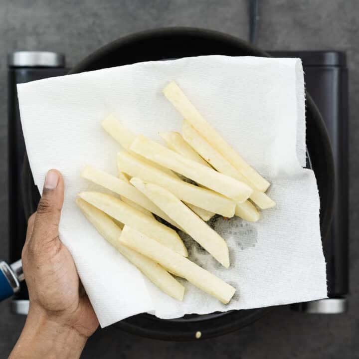 Fried potatoes for chips in a paper-lined tray, ready for refrigerating.