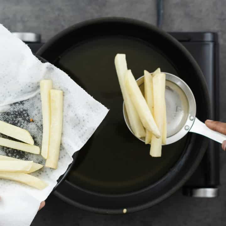 Adding the cooled chips for double frying in the oil.