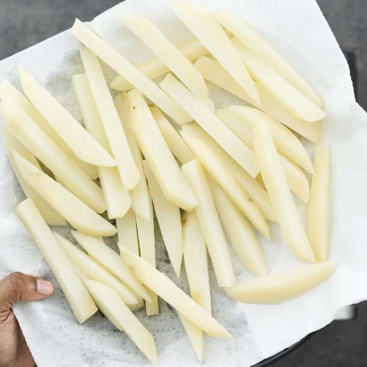 Blanched potatoes drained on a paper towel-lined plate.