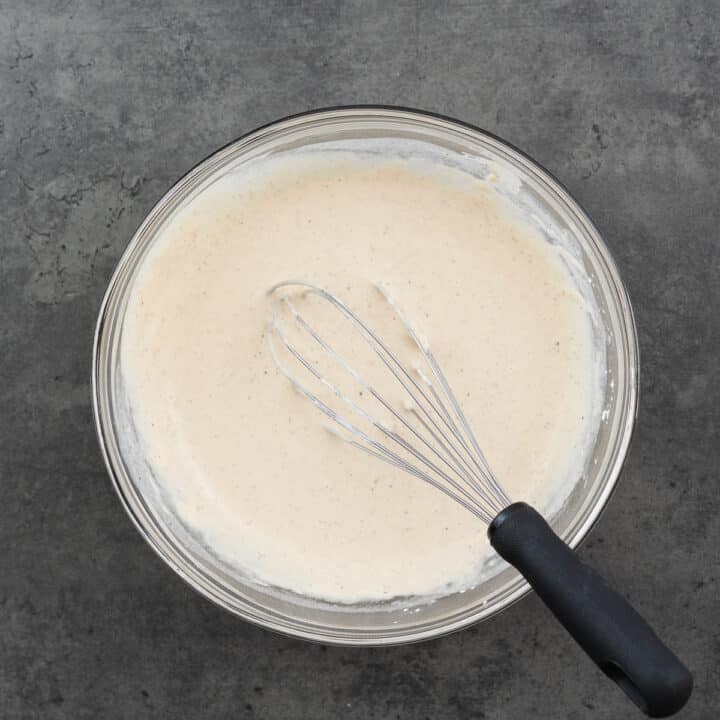 A bowl with batter for coating fish, with a whisk beside it.