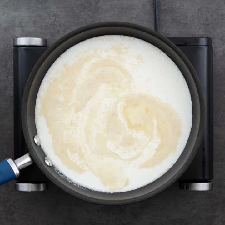 A pan containing roux with milk and half-and-half added, starting to combine.