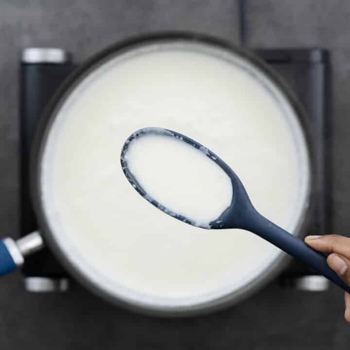 A close-up of cream sauce's consistency, shown on a blue spoon.