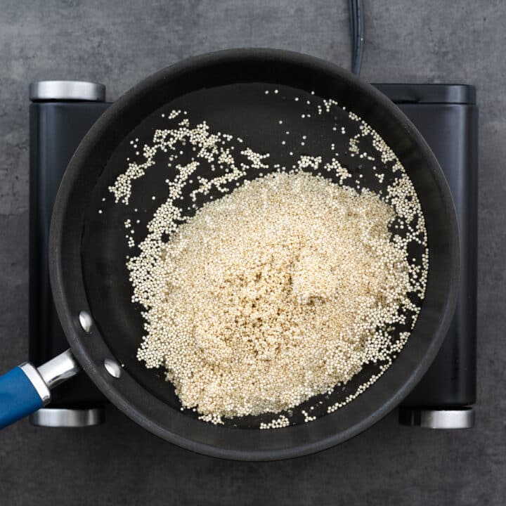 A pan with quinoa submerged in water, prepared for boiling.