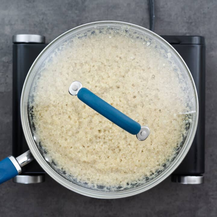 A pan with quinoa covered and cooking on the stove.