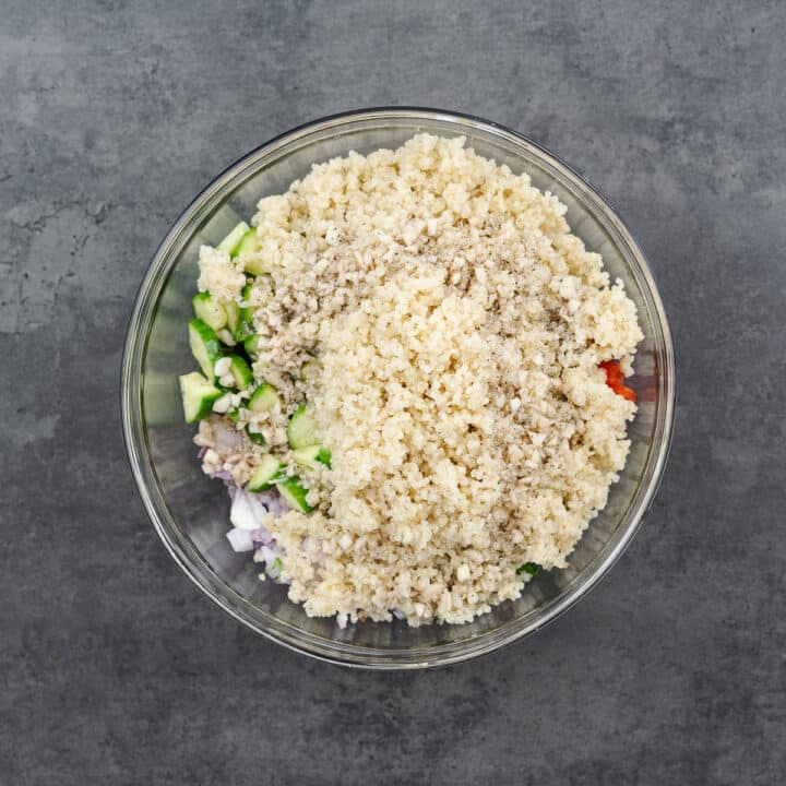 A bowl with layers of crisp vegetables, chickpeas, quinoa, and salad dressing.