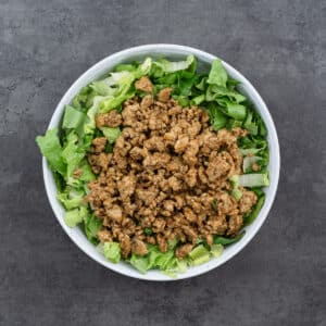 A bowl with layered lettuce and ground meat.
