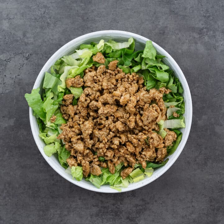 A bowl with layered lettuce and ground meat.