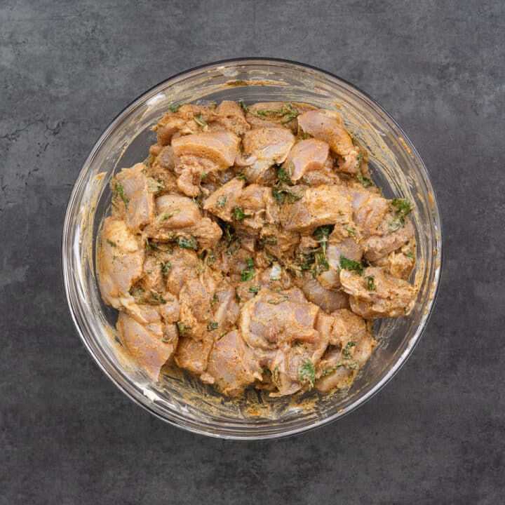 A bowl with marinated boneless chicken pieces.