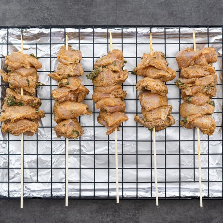 A baking tray with chicken skewers and ready for cooking.