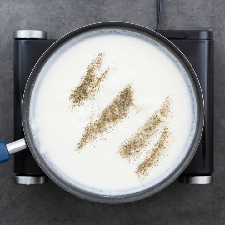 A pan with creamy white gravy seasoned with salt and black pepper.