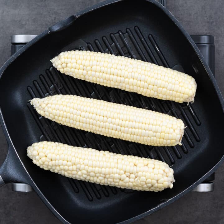 A grill pan with corn on the cob, showing the corn being grilled.