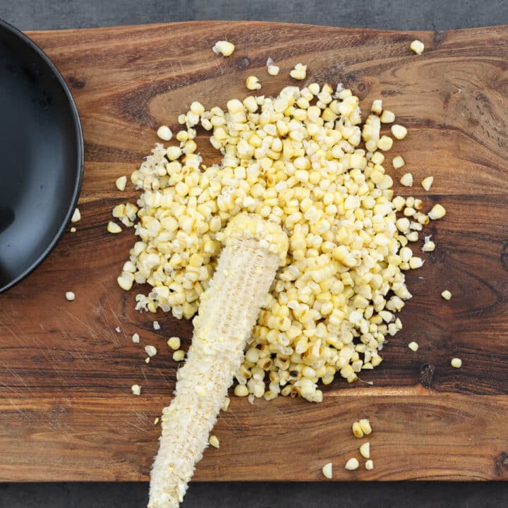 A wooden board with freshly sliced corn kernels, neatly cut from the cob and ready to use.