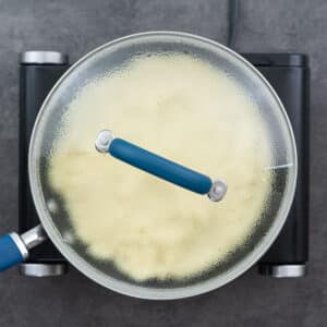 A saucepan with a lid on, containing couscous cooking in the residual heat.