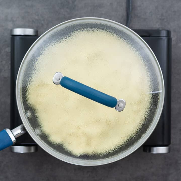 A saucepan with a lid on, containing couscous cooking in the residual heat.