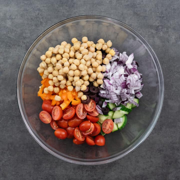 A mixing bowl filled with chopped vegetables and cooked garbanzo beans.