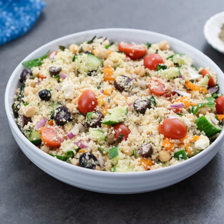 A serving of Mediterranean couscous salad in a white bowl, showcasing the vibrant, finished dish.