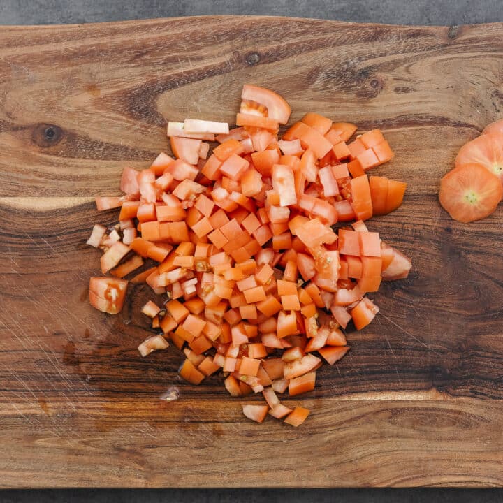 Freshly chopped Roma tomatoes arranged on a wooden cutting board.