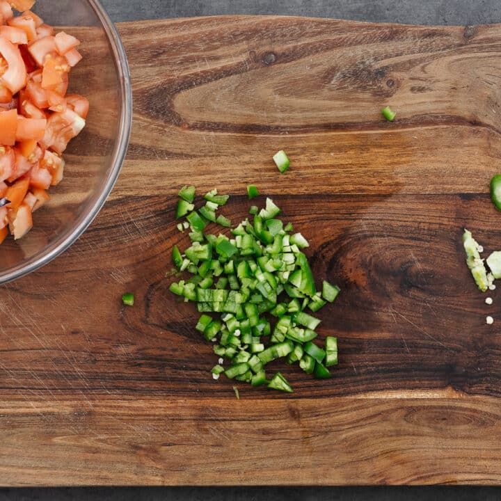 Sliced and chopped jalapeño peppers on a wooden cutting board, with seeds and veins removed.