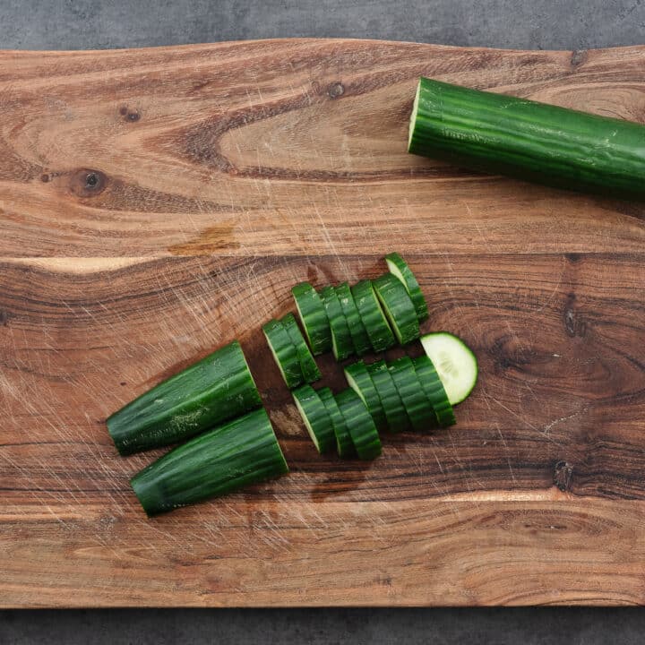 A cutting board with fresh cucumber slices.