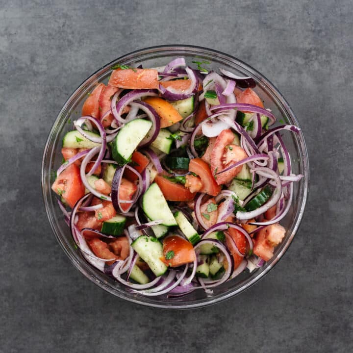 A bowl of cucumber tomato salad tossed in vinaigrette.