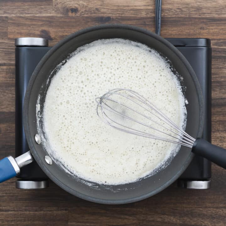 A pan with roux made from butter, being whisked until smooth.