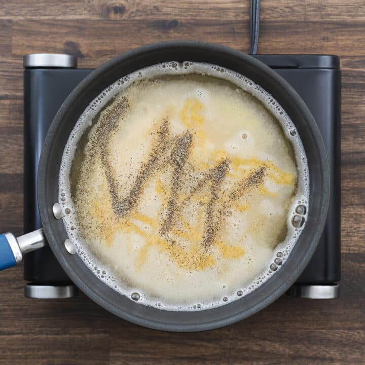 A pan with gravy mixture seasoned with garlic, black pepper, Worcestershire sauce, and chicken bouillon powder.