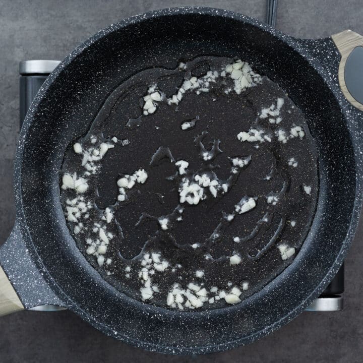 Garlic being sautéed in a pan, releasing its aromatic flavor.