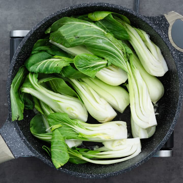 Quartered bok choy arranged in a single layer in the pan, prepared for searing.