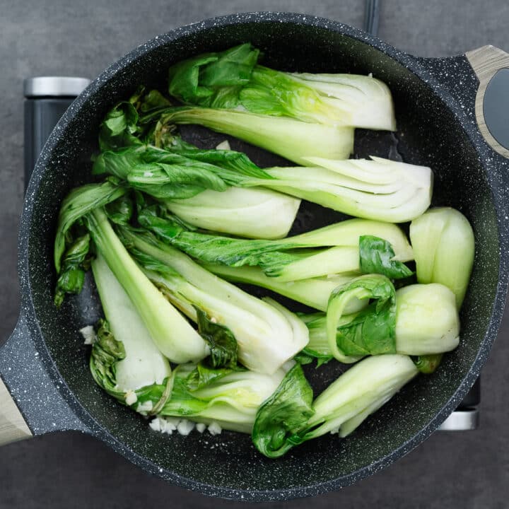 Quartered bok choy being seared to perfection, with edges slightly browned.