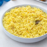 Homemade saffron rice in a white bowl on a white table.