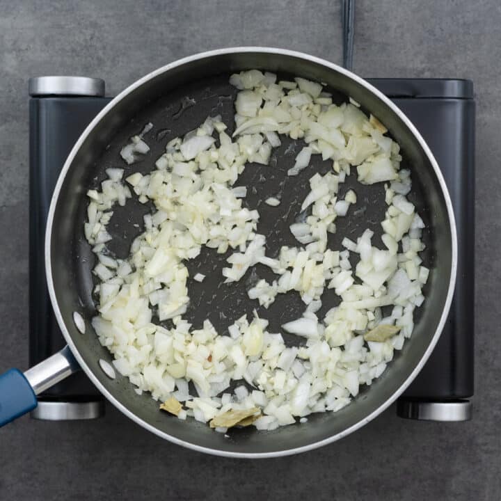 Pan with onions, garlic, and bay leaves sautéed until aromatic.