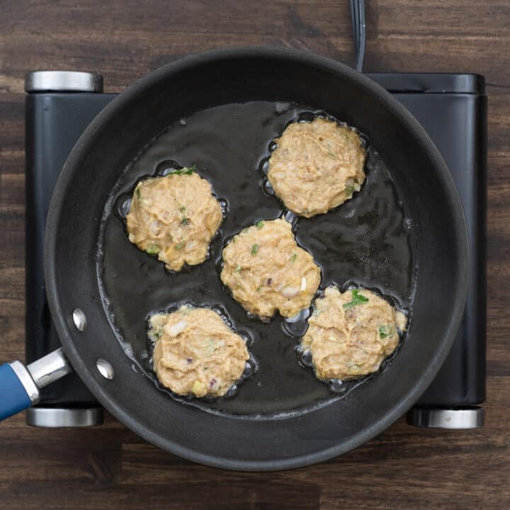 A pan with chicken patties frying in oil.