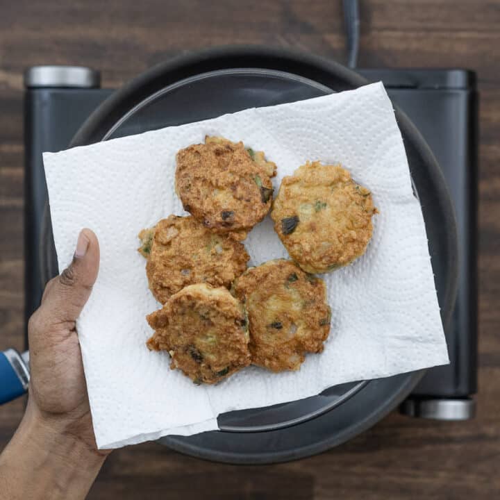 Soft and crispy chicken patties resting on tissue paper, lined on a black plate to drain excess oil.