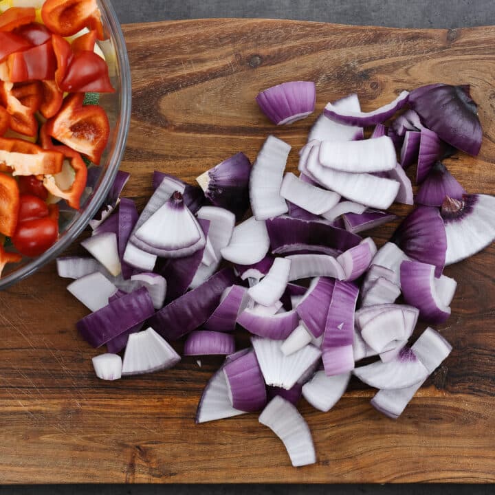 A wooden board with diced onion, showing the layers separated for easy threading onto skewers.