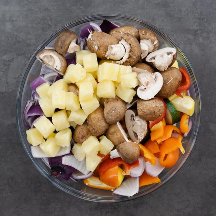 A bowl filled with an assortment of chopped vegetables, all ready for threading onto skewers.