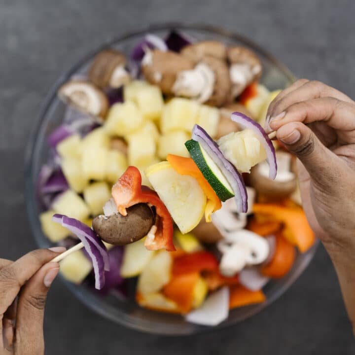 A wooden skewer threaded with colorful, chopped veggies.