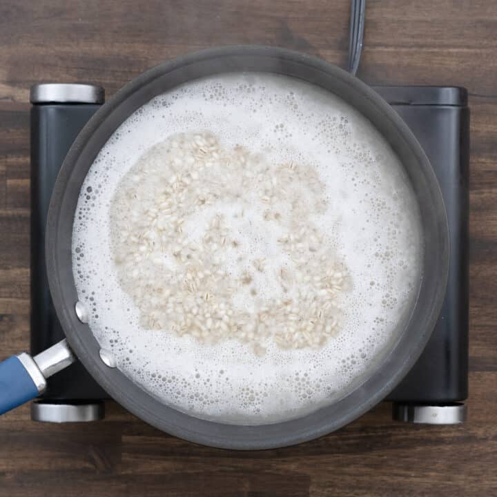 A pan with barley in boiling water, bubbling rapidly.