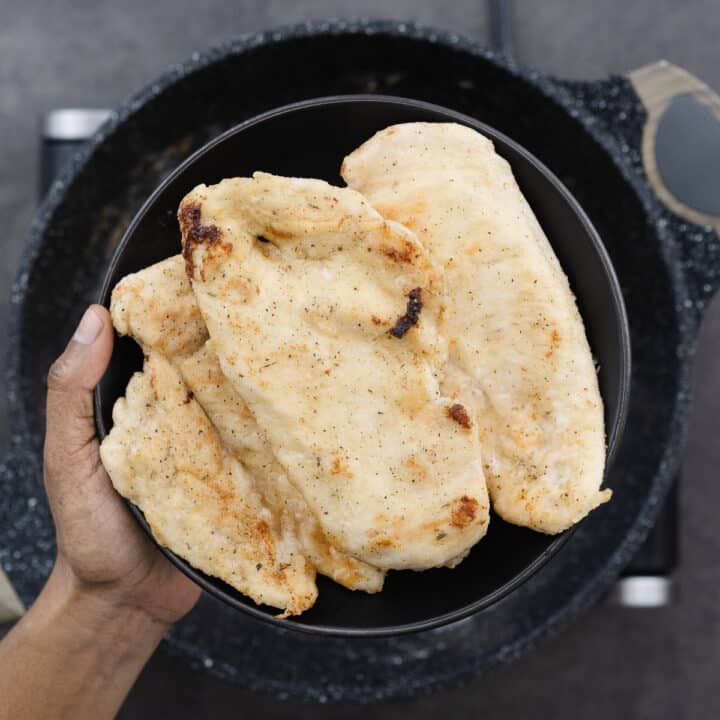 Nicely golden fried chicken breasts placed on a black plate, ready for the next step.