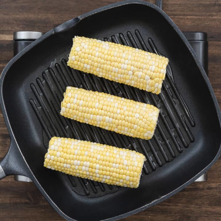 Corn arranged on a grilling pan, with space between each ear to prevent overcrowding.